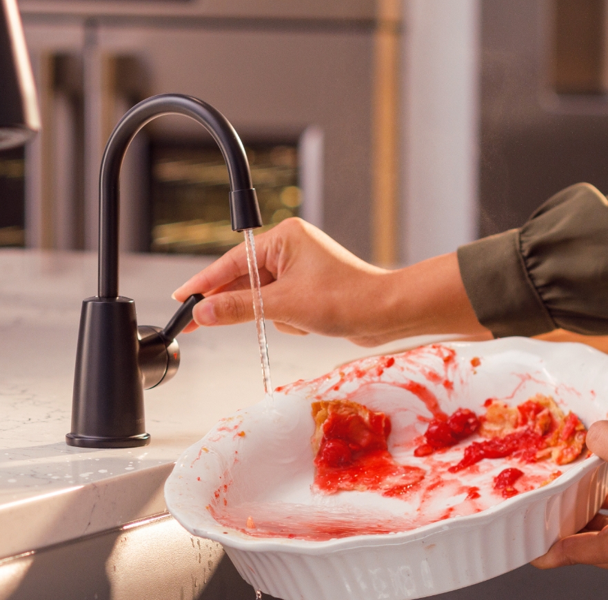 Faucet rinsing a pie dish.
