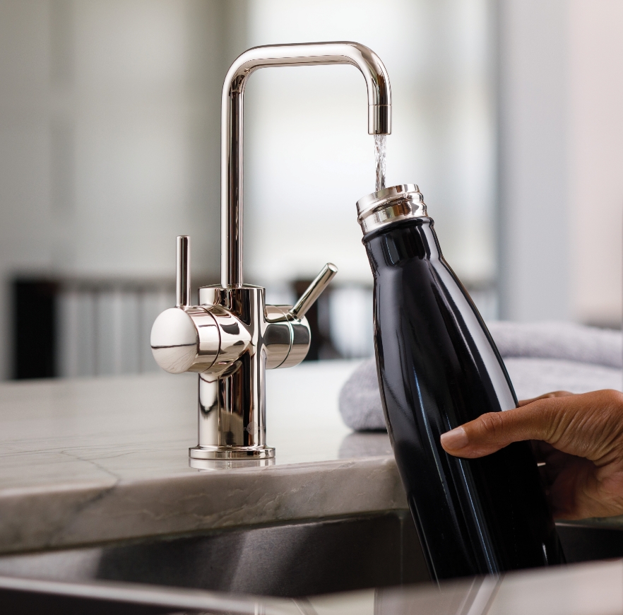 Water bottle being filled at a faucet.